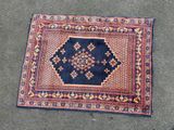 a blue and red rug on the ground with a black background