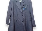 un manteau gris à revers bleu, suspendu à un cintre sur un mur blanc