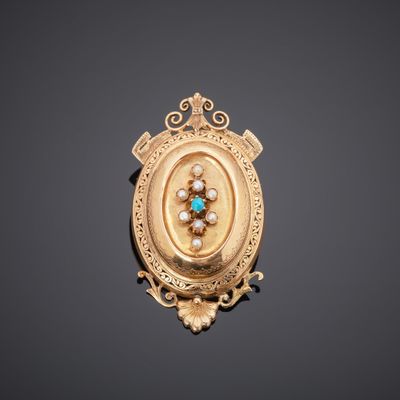 a gold broochle with a turquoise and white stone in the center