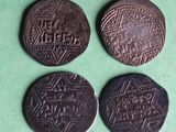 three old coins are shown on a green surface