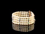 un gros plan d'un bracelet orné de perles sur un fond noir