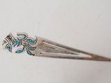 une barrette argentée ornée d'un motif bleu et blanc