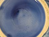 a close up of a blue vase with a yellow rim