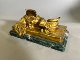 une figurine en or posée sur un socle en marbre