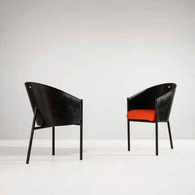 deux chaises noires avec des coussins orange dans une pièce blanche