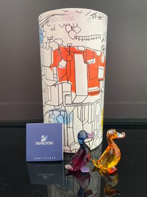 un vase en verre, avec une petite figurine posée à côté, sur une table