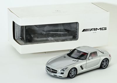 une petite voiture argentée devant une boîte blanche