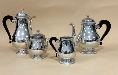 trois cafetières en argent et deux tasses en argent posées sur une table
