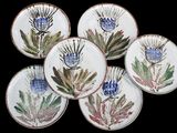 six plates with flowers painted on them on a black background