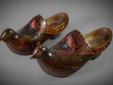 pair of wooden shoes with painted birds on them sitting on a table