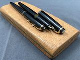 two pens are sitting on a wooden box on a blue surface