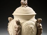 un vase blanc surmonté d'une statue