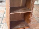 une petite bibliothèque en bois posée à même le sol dans une pièce