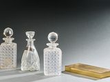 trois bouteilles en verre et une boîte dorée posées sur une table
