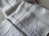 two white napkins with embroidered designs on them on a bed
