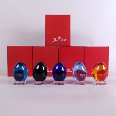 four glass eggs are lined up in a row in front of a red box
