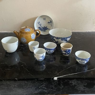 une table noire sur laquelle sont posées plusieurs tasses et une théière