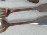 three silver spoons and two silver forks on a white cloth