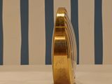 a gold vase sitting on a table with a striped wall behind it