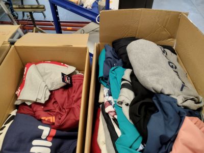 Des cartons de vêtements sont empilés les uns sur les autres dans un entrepôt