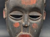 a close up of a wooden mask on a black background