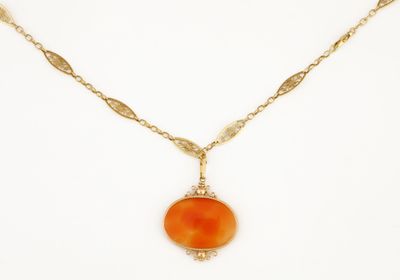 un collier en or avec un pendentif en pierre orange monté sur une chaîne en or