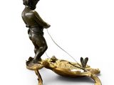 bronze figurine of a boy pulling a dog on a leash