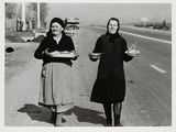black and white photograph of two women holding plates of food