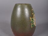 a green vase with a flower on it on a gray surface