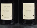 two bottles of wine sitting on top of a table next to each other