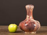 an apple next to a vase on a table