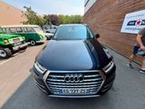 un homme debout à côté d'une Audi noire garée sur un parking
