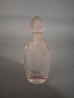 une bouteille en verre rose ornée d'un motif floral