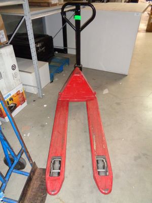 un chariot élévateur rouge garé au milieu du sol d'un entrepôt
