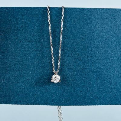 un pendentif en forme de diamant blanc est suspendu à une chaîne en argent sur un fond bleu
