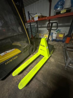 un chariot élévateur jaune garé dans un entrepôt à côté d'une palette