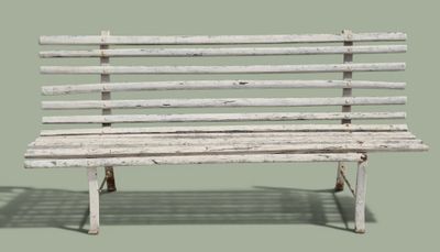 un banc en bois blanc dont l'ombre se projette sur le sol