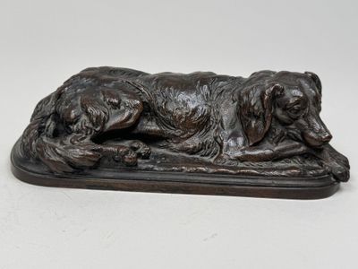 statue en bronze représentant un chien couché sur un socle en bois
