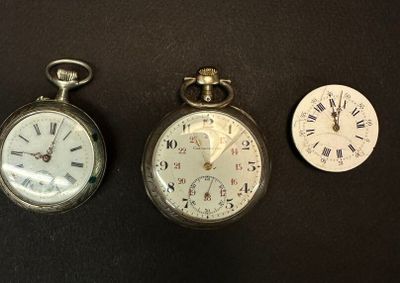 trois montres de poche différentes posées sur une surface noire