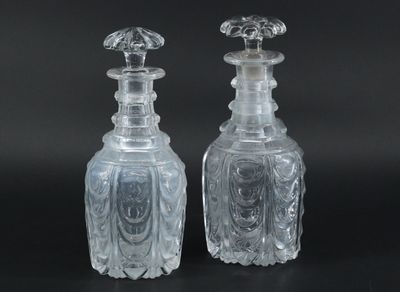 pair of clear glass bottles on a black surface with a black background