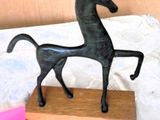 statue of a horse standing on a wooden block on a table