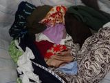 a basket full of clothes on a bed with a pillow
