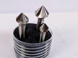 quatre pièces métalliques se trouvent dans un support métallique posé sur une surface blanche