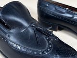 pair of black leather shoes with tassels on them on a white surface