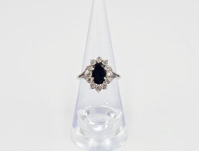 gros plan d'une bague avec une pierre noire entourée de diamants blancs