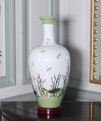 un vase blanc orné de libellules, posé sur une table