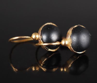 une photo d'une paire de boucles d'oreilles en or et pierres noires