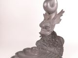 statue d'une femme avec un oiseau sur la tête, assise sur une fleur