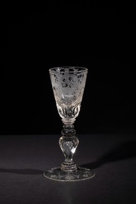 a wine glass sitting on a table with a black background