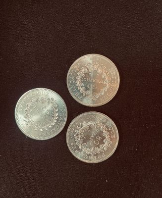three silver coins sitting on top of a black surface